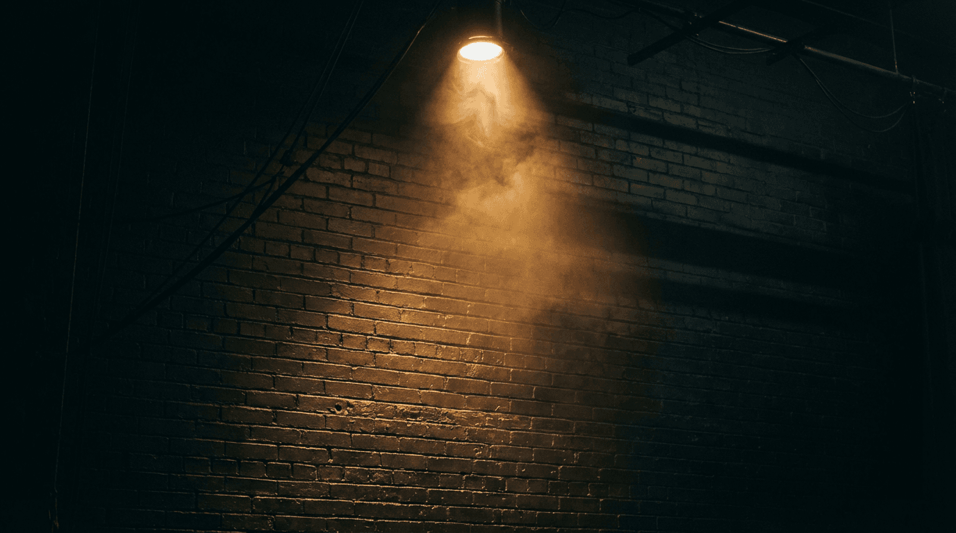 Dramatic spotlight cone illuminating brick wall with swirling dust and theatrical shadows